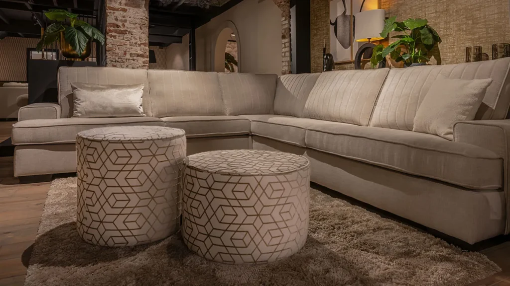 UrbanSofa Brandon Hoekbank met Manhattan Rugkussen in Palazzo Sand en Otis Poefen in Fairmont Shiny Desert